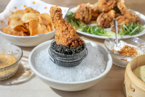fried chicken wing being dipped in caviar