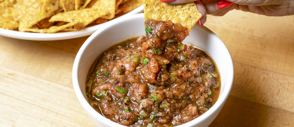 chip dipping into savory charred salsa