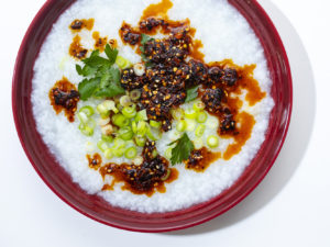 bowl of rice porridge with momofuku chili crunch and sliced scallions